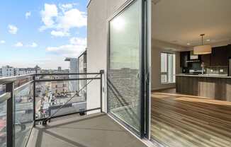 A modern balcony with glass doors overlooking a cityscape.