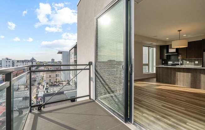 A modern balcony with glass doors overlooking a cityscape.