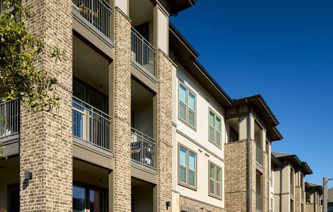 A row of apartment buildings with balconies and flower boxes.