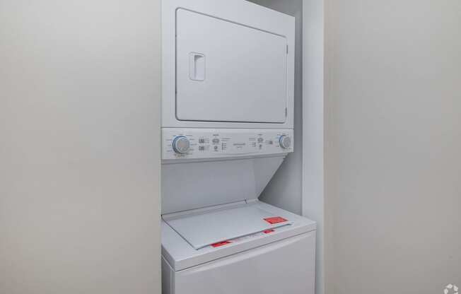 A white dryer and washing machine are stacked on top of each other.