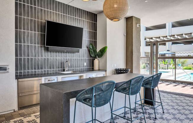A modern kitchen with a bar area and chairs.