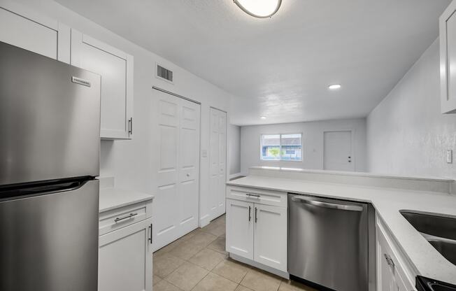 an empty kitchen with white cabinets and stainless steel appliances