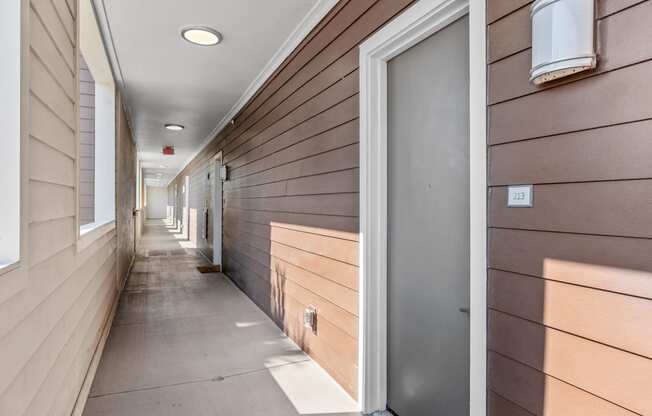 a long hallway with wood paneled walls and a silver door