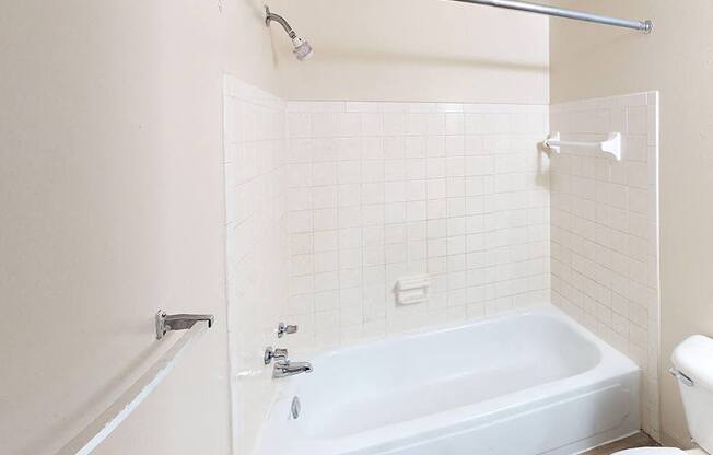 A full bathroom with a tub, toilet, and shower at Glen Oaks Apartments, Michigan, 49442