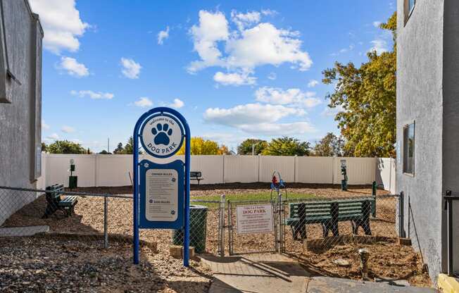 a blue sign in front of a playground with benches and a fence