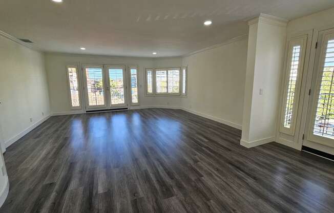 an empty living room with wooden floors and windows