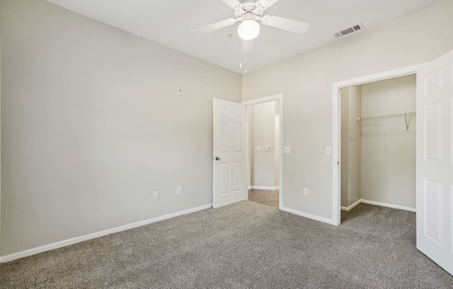 A room with a ceiling fan and carpeted floor.