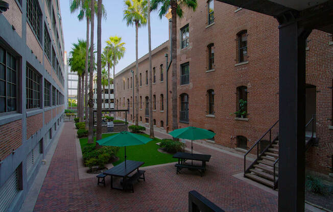 A courtyard with a green umbrella and benches.