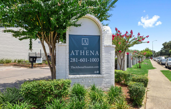 a building with a sign and some trees and plants