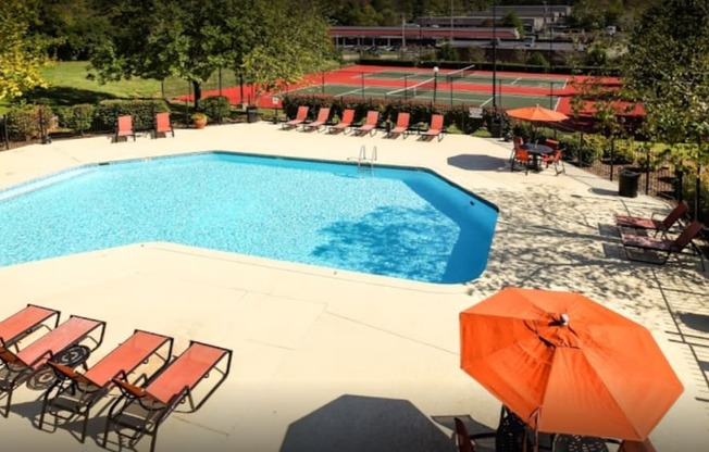 a swimming pool with chairs and an umbrella in a garden at Landmark at Lyncrest Reserve Apartments, Nashville, TN, 37209