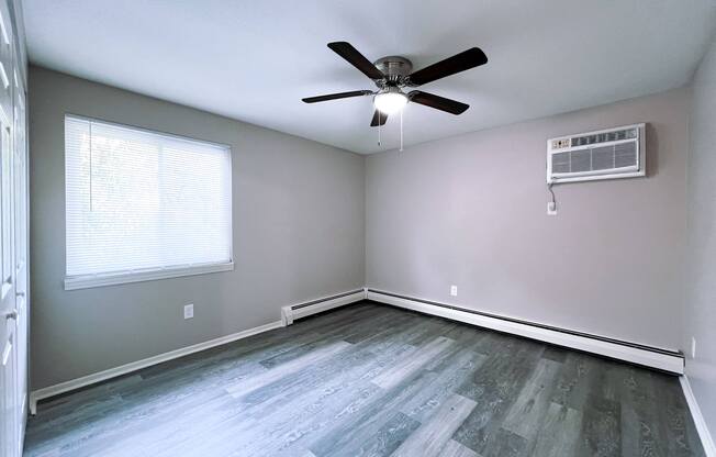 an empty living room with wood floors and a ceiling fan