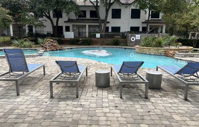 a swimming pool with blue lounge chairs and a resort style pool