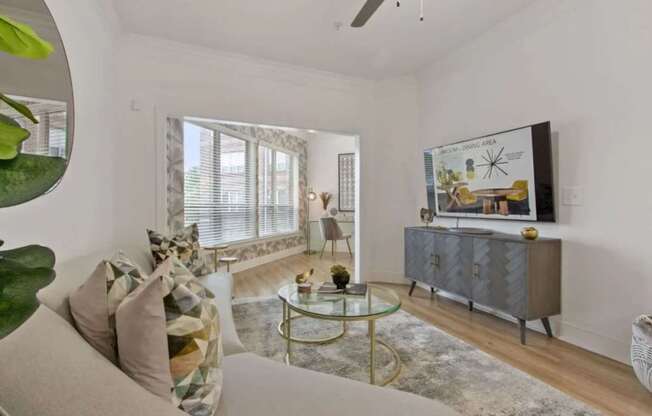 A living room with a grey cabinet, a glass table, and a painting on the wall.