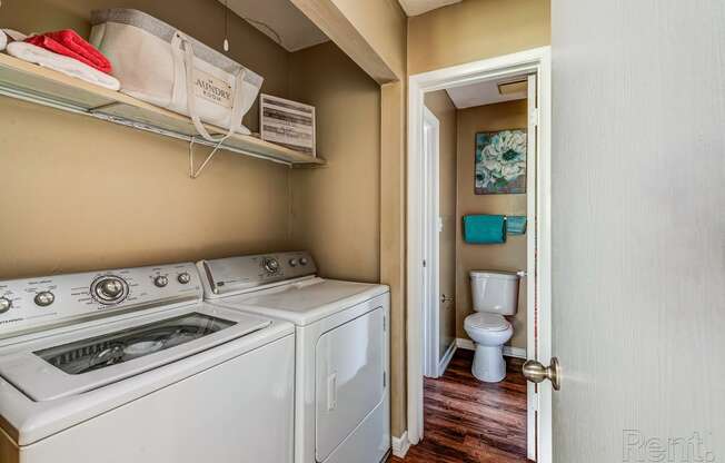 a laundry room with a washer and dryer and a toilet in a bathroom