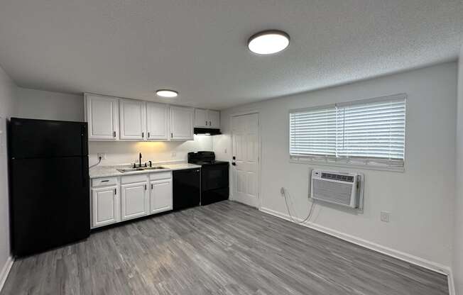 an empty kitchen with white cabinets and black appliances