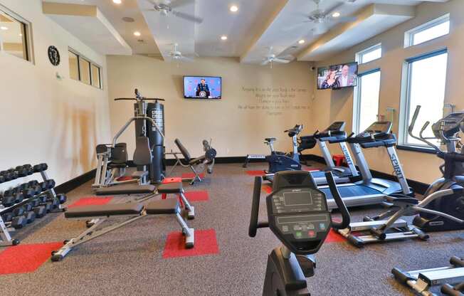 a gym with exercise equipment and a tv on the wall