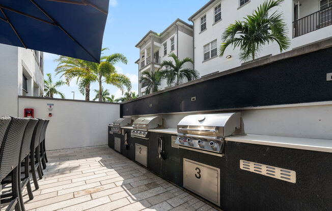 three barbecue grills on a patio in front of a building