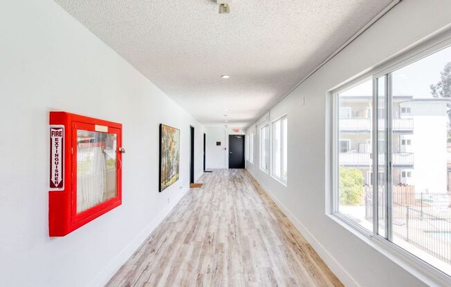 a long hallway with large windows and a red picture frame on the wall