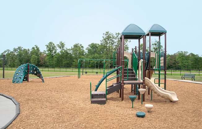A playground with a green slide and a brown wooden structure.