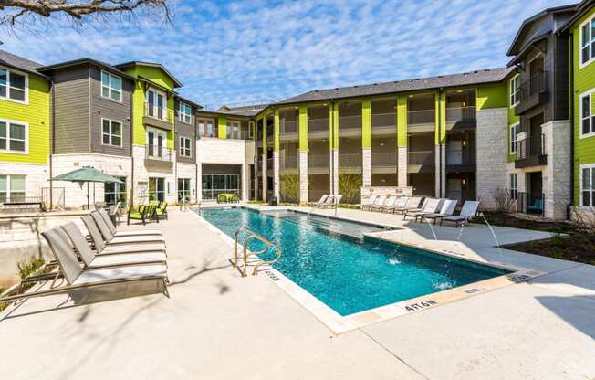 Pool with poolside lounge seating and umbrella shaded tables