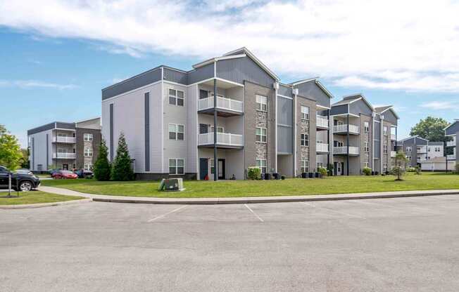 A large apartment complex with multiple buildings and a parking lot in front.