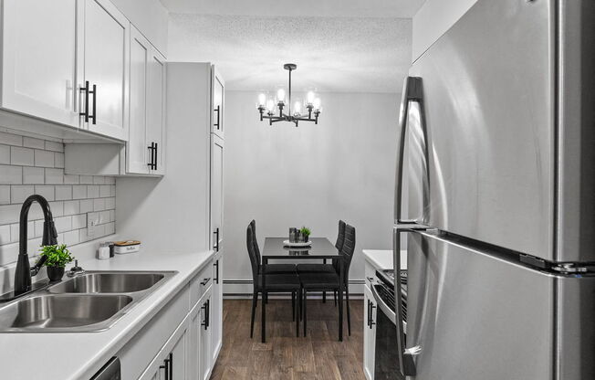 a kitchen with white cabinets and stainless steel appliances and a dining room table