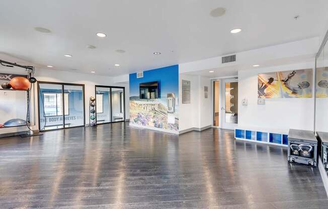 A spacious room with a wooden floor and a blue wall with a mural.