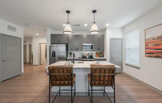 an open kitchen with a large island with two chairs in front of it