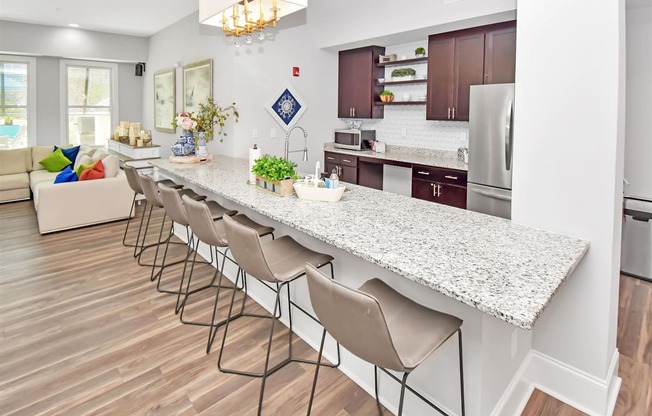a kitchen with a large island with a breakfast bar and a living room in the background