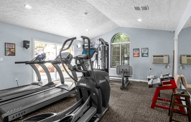 a gym with treadmills and other exercise equipment in a room with a window