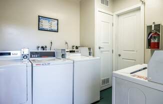 a laundry room with four washers and dryers and a door to a bathroom