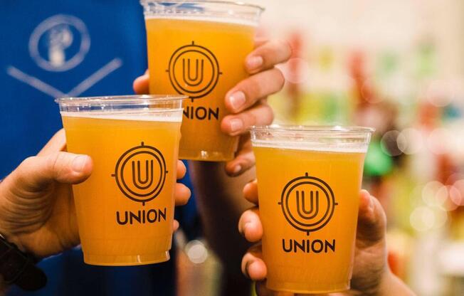 A person holding three cups of Union beer.