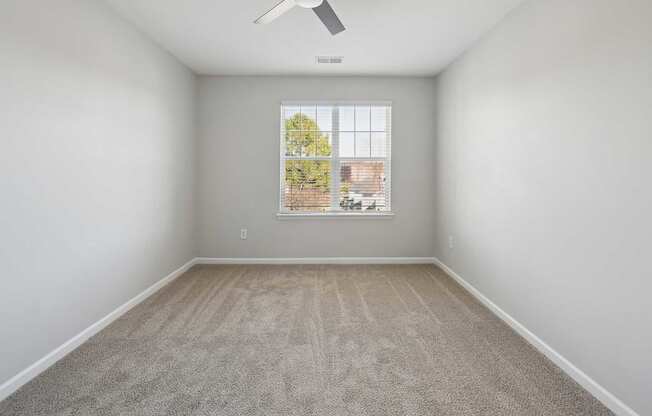 A room with a window and a fan on the ceiling.
