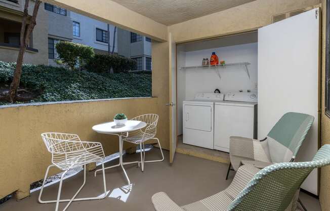 A small balcony with a table and chairs.