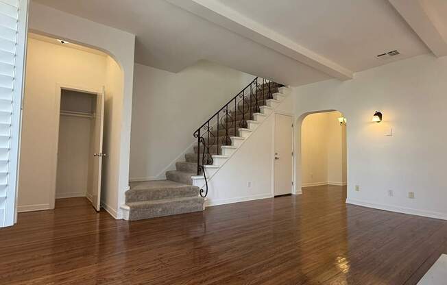 A spacious room with a staircase and wooden flooring.