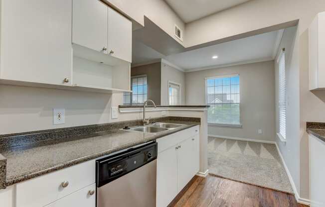 an empty kitchen with white cabinets and granite counter tops