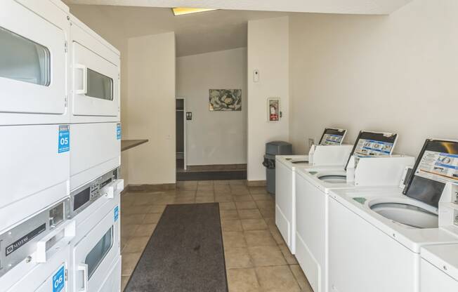 a laundry room with a lot of washes and dryers and a sink