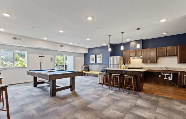 a game room with a pool table and a kitchen