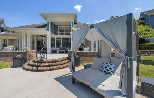 a patio with a couch and umbrellas in front of a house