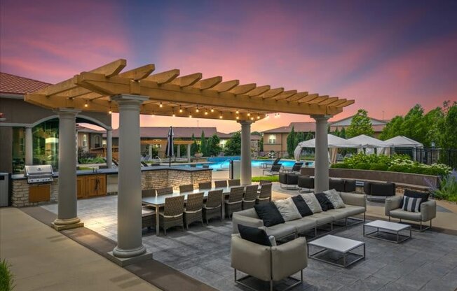 a patio with couches and chairs under a wooden canopy