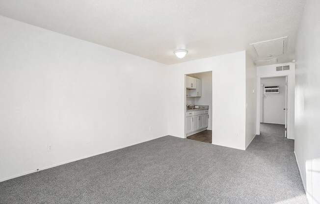 A white room with a grey carpet and a door on the right.