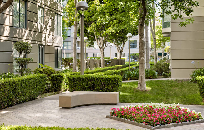 A well-manicured garden with a bench and a flower bed in the foreground.