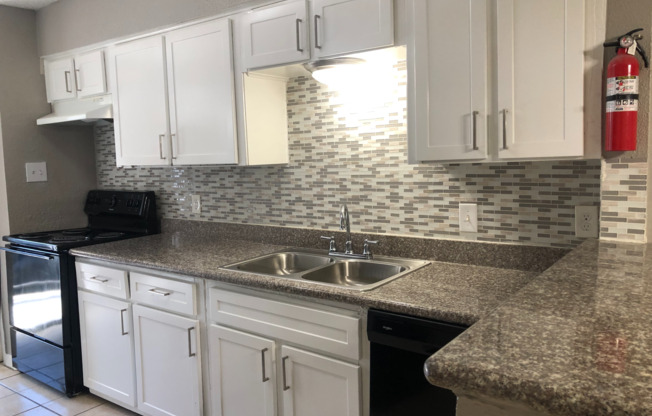 Kitchen with granite countertops, tile backsplash, shaker cabinets, and cabinet hardware