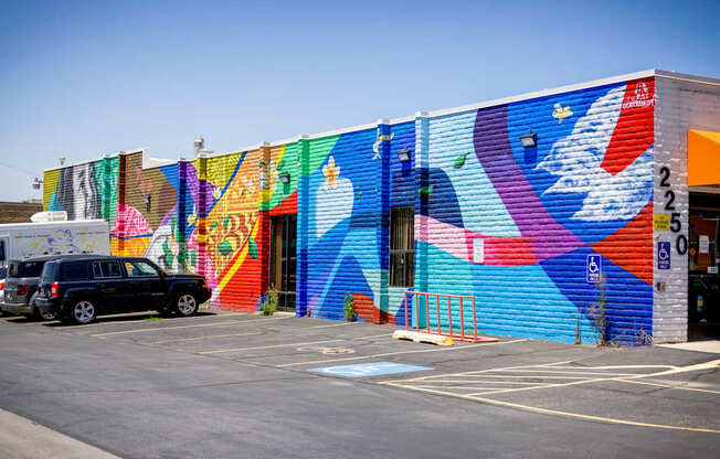 A colorful mural on a building with a car parked in front.