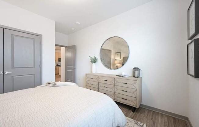 a white bedroom with a white bed and a mirror