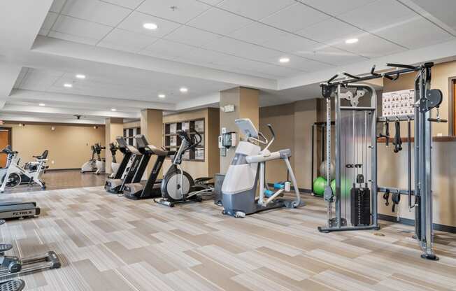 a gym with cardio machines and weights on a wooden floor