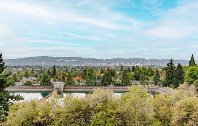 A serene landscape with a lake, trees, and a distant city skyline.