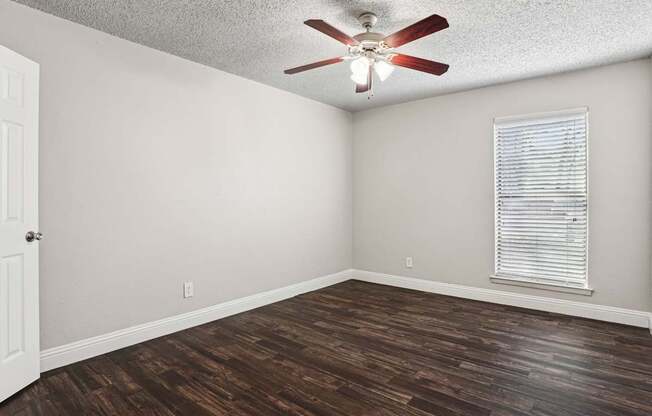 A room with a ceiling fan and a window with blinds.