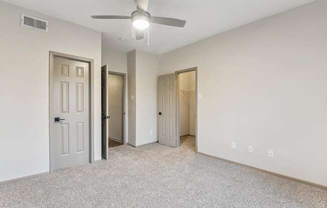A room with a ceiling fan and three doors.