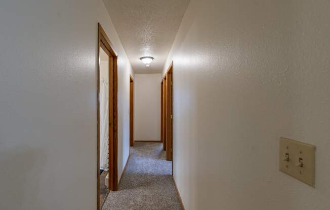 the upstairs hallway of a house with a carpeted floor and wooden doors. Fargo, ND Crescent Park Apartments